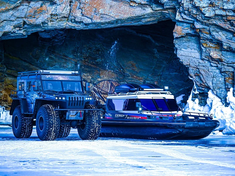 Вездеход и лодка у пещеры зимой Иллюстрация Вездеход и лодка у пещеры зимой